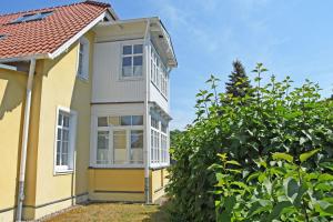 a yellow house with white windows and a tree at ruhig gelegenes Appartementhaus mit Ferienwohnungen VSo in Göhren