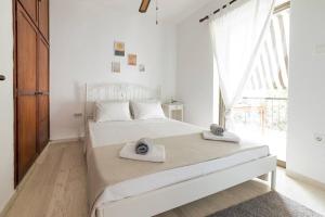 a white bedroom with a bed with towels on it at Seaside escape apartment in Saronida