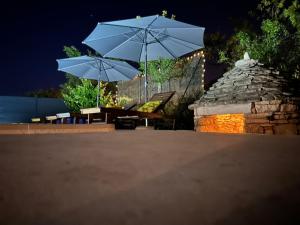 a patio with two umbrellas and a table and chairs at Holiday house Diva with a pool in Svetvinčenat