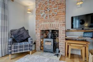 - un salon avec une cheminée en briques et une horloge murale dans l'établissement April Cottage by Winterton Cottages, à Winterton-on-Sea