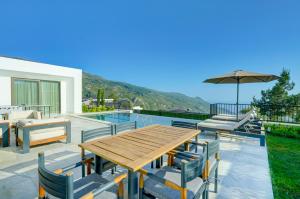 a patio with a wooden table and chairs and a pool at Villa Pluto 1 - PLANET LUXURY VILLAS in İslâmlar