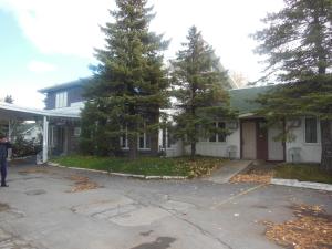 une maison blanche avec des arbres devant elle dans l'établissement Motel Le Paysan, à Montréal