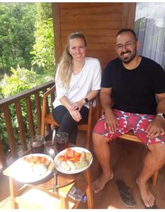 a man and a woman sitting on a porch with food at Uma d'Nyuh Homestay in Singaraja +34 photos