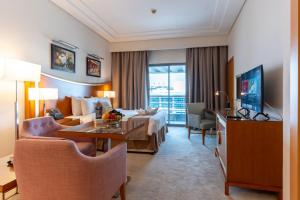 ドバイにあるグランド ベル ビュー ホテル アパートメント ドバイのベッドとリビングルームが備わるホテルルームです。