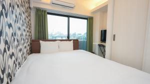 um quarto com uma cama branca e uma janela grande em CoCo SPACE em Kagoshima