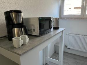 a counter with a microwave and two cups on it at Serene Meadows Apartment in Solingen