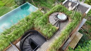 an aerial view of a pool with a person in a bath tub at Rumah Subak Tampaksiring in Tampaksiring