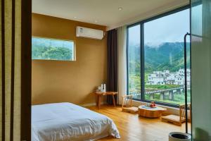 Nature Cure Village Lodge-婺源自在舍 في ويوان: غرفة نوم بها سرير ونافذة كبيرة