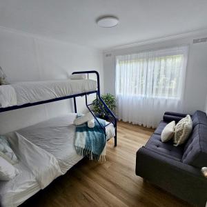 1 dormitorio con 2 literas y sofá en Prom Coast - Seabreeze, en Sandy Point