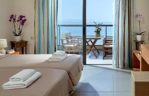 a bedroom with two beds and a view of the ocean at Creteco Hotel & Suites in Gournes