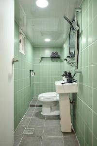 a green tiled bathroom with a toilet and a sink at Your-jin stay Seoul in Seoul