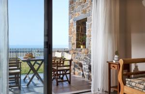 a room with a balcony with a table and chairs at Creteco Hotel & Suites in Gournes