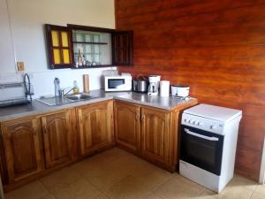 a kitchen with wooden cabinets and a sink and a stove at Bungalow charmant avec jardin à Saint-Louis, piscine partagée in Saint-Louis