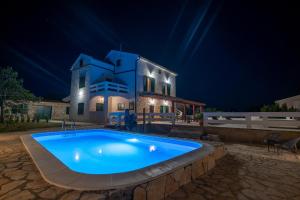 a swimming pool in front of a house at night at Apartment Kosljun with pool in Košljun