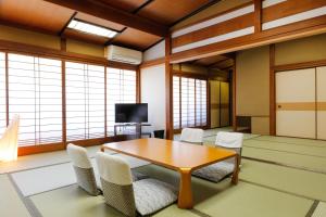 a room with a table and chairs and windows at Tsuruya Ryokan in Toyooka
