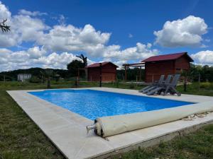 a swimming pool with two chairs and a house at gites le ciel clair in Mortroux