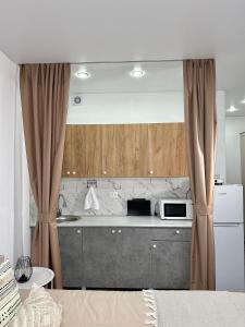 a kitchen with a microwave on a counter with curtains at Студия in Karagandy