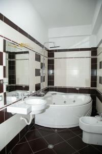 y baño con bañera, lavabo y aseo. en Grand Hotel, en Elbasan