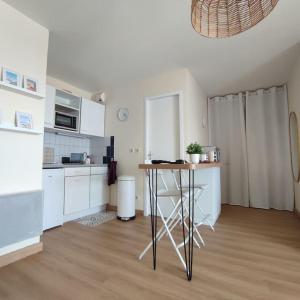 a kitchen with white cabinets and a table in a room at Vue Panoramique FACE MER in Bray-Dunes