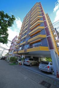 a large building with cars parked in a parking lot at Jade Tower in Chiang Mai