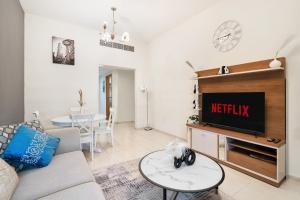 a living room with a couch and a tv at Cozy 1 Br Apartment In Axis 2 Residence Dso in Dubai
