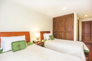 a bedroom with two beds and a wooden cabinet at Hotel Portofino in Bogotá