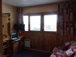 a bedroom with a bed and a window and a television at Buron in Les Menuires