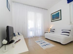 - un salon avec un canapé blanc et une télévision dans l'établissement Apartments Villa Olea, à Lumbarda