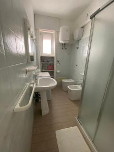 bagno bianco con 2 lavandini e servizi igienici di Donizetti Vacation Apartment a Porto Cesareo Altre 6 foto