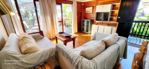 a living room with two white couches and a television at Milkwood Lodge 5 - Sleeps 6 in Port Edward