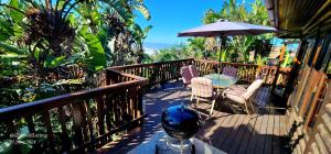 a balcony with a table and chairs and an umbrella at Milkwood Lodge 5 - Sleeps 6 in Port Edward