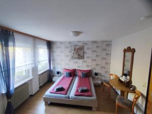 a bedroom with a bed with red sheets and a table at Zum Anker - Mosel Restaurant & Weinstube in Briedel