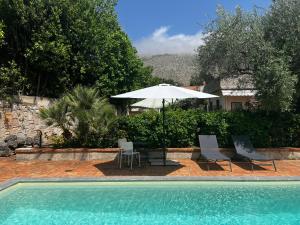 una piscina con dos sillas y una sombrilla en Villa Costanza, en Mondello