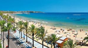 a beach with palm trees and a crowd of people at Apartaments Segur Kandy 1 in Calafell