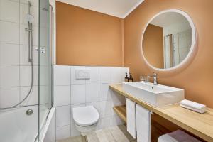 ein Bad mit einem WC, einem Waschbecken und einem Spiegel in der Unterkunft the Deutz, a Tribute Portfolio Hotel in Köln