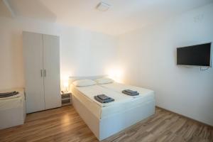Un dormitorio blanco con una cama y un televisor de pantalla plana. en Milutinn-Jabuka, en Soko Banja