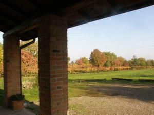 a brick building with a field and trees in the background at Agriturismo Bosco Del Fracasso in Scandiano