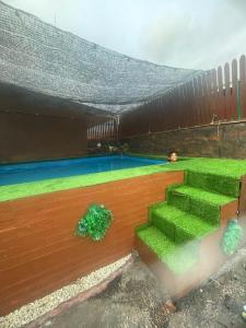 un patio trasero con una piscina con césped verde en Homestay Kakak Adek with private pool sempadan Perak,Penang dan Kedah, en Bandar Baharu