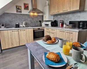 a kitchen with a table with bread and orange juice at Le Scénario - centre ville in Sarreguemines