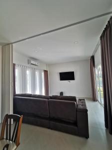 a living room with a black couch and a flat screen tv at Pool Villa Mountainview in Cha Am +43 photos