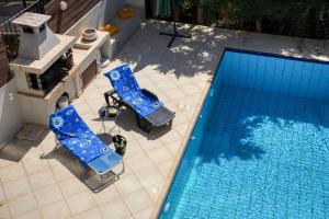 einen Blick über einen Pool mit zwei blauen Stühlen in der Unterkunft Saronida Hills private Pool in Saronida