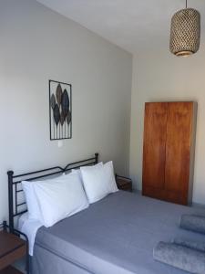 a bedroom with a bed with white pillows and a wooden door at Andromeda in Ios Chora