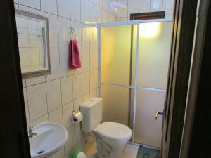 a bathroom with a shower and a toilet and a sink at Pousada Laranja Lima in Praia do Rosa
