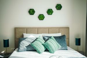 a bed with green pillows and a heart above it at Taikos apartamentai in Klaipėda