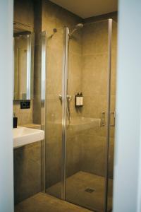 a shower with a glass door next to a sink at Taikos apartamentai in Klaipėda +43 photos