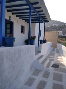 a white building with blue columns and potted plants at Andromeda in Ios Chora