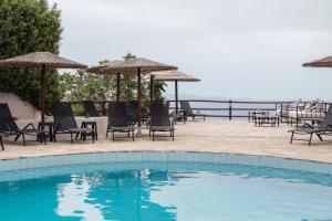 a swimming pool with chairs and umbrellas and the ocean at Thalia Bloom Villa Apartments in Agia Pelagia