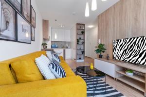 a living room with a yellow couch and a kitchen at LAM Safari - BALCONY - AC - FREE PARKING in Bratislava +15 photos