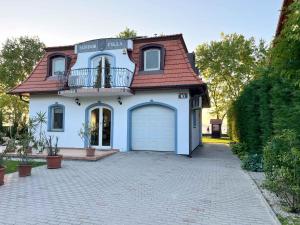 a blue house with a garage and a balcony at Holiday home in Balatonboglar 48107 in Balatonboglár