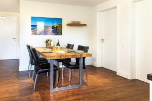 a dining room with a wooden table and black chairs at Haus Oldenburg - Wohnung 3 mit Balkon in Wangerooge